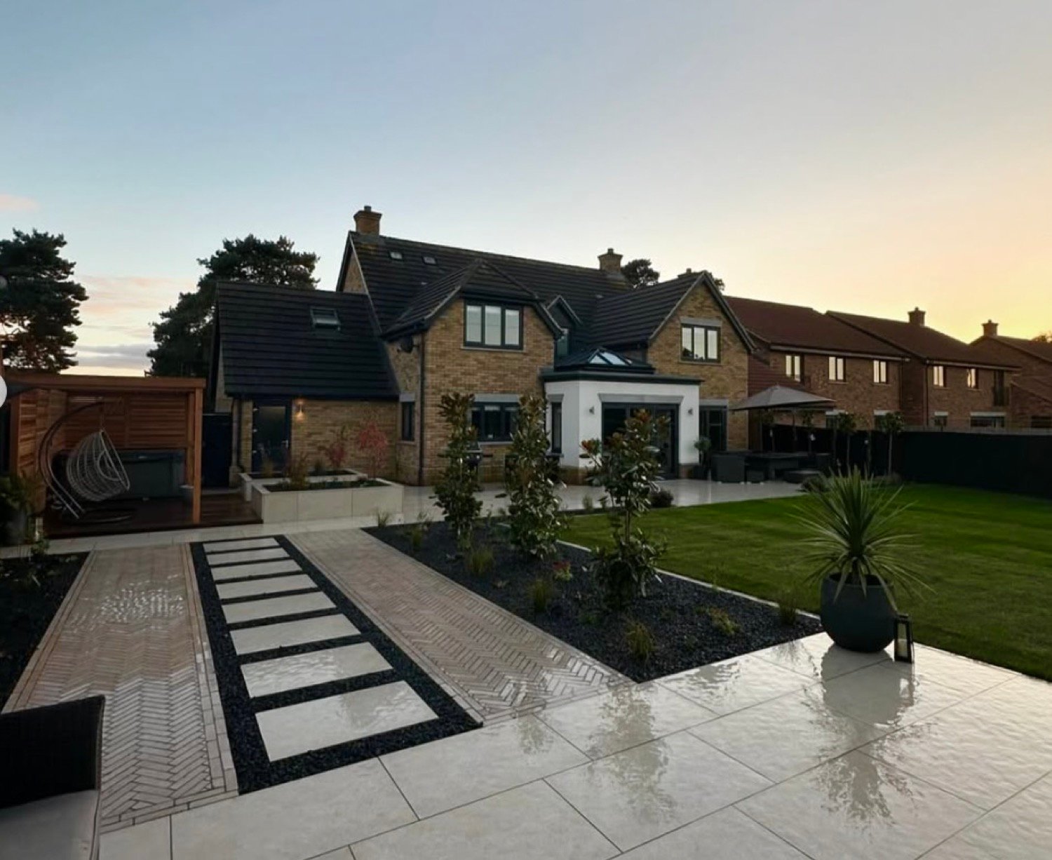 Large garden at dusk with stepping stone path, hot tub pergola and lawn