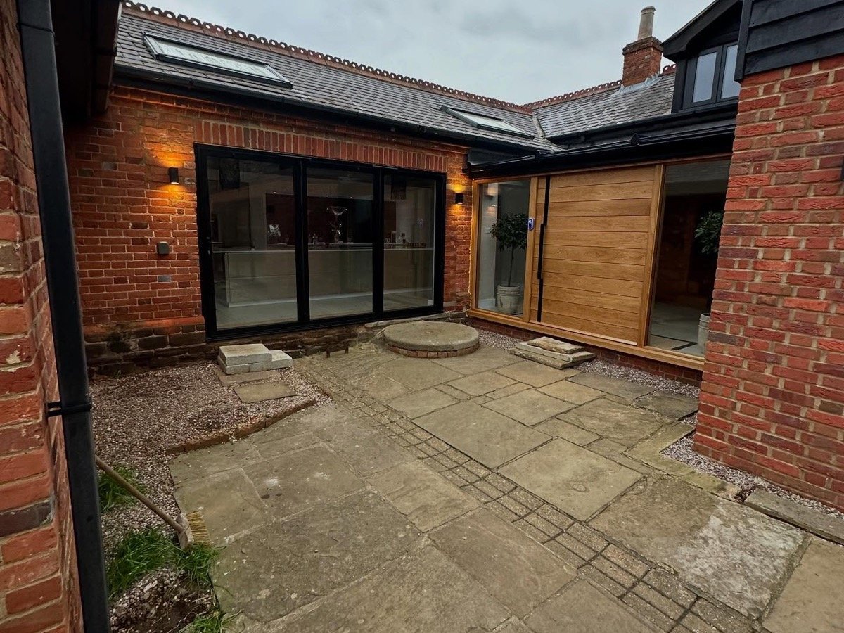 A courtyard with cracked, weathered slabs before RB Landscapes started work
