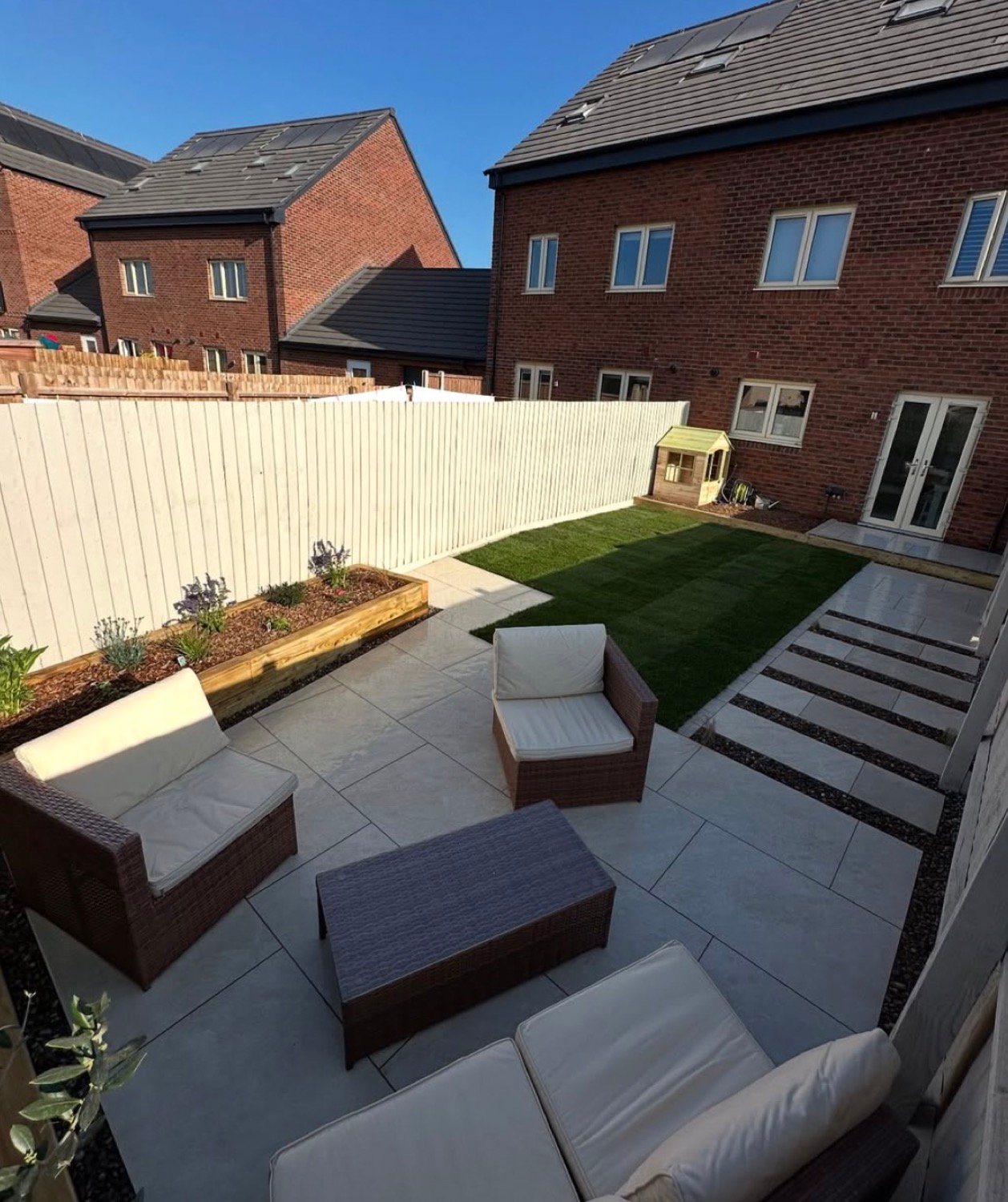 Family garden with porcelain patio, stepping stones, lawn and playhouse
